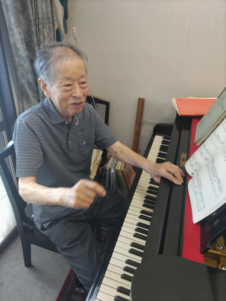 ピアノの前で笑顔の田辺先生